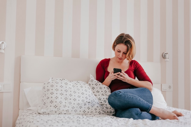 Linda mujer con smartphone en la cama