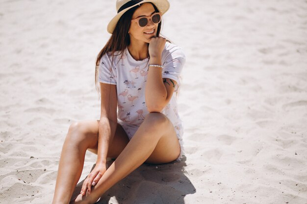 Linda mujer con sombrero sentado en la arena