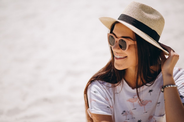 Foto gratuita linda mujer con sombrero sentado en la arena