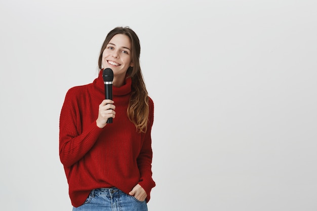 Linda mujer sonriente cantando karaoke, sostenga el micrófono