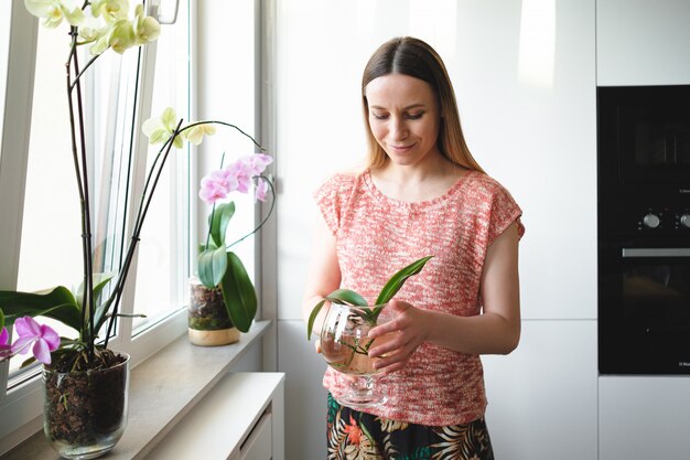 Linda mujer sosteniendo en las manos una lata de agua con una planta de orquídea