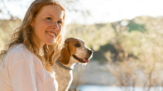 Linda mujer y su perro en la naturaleza.