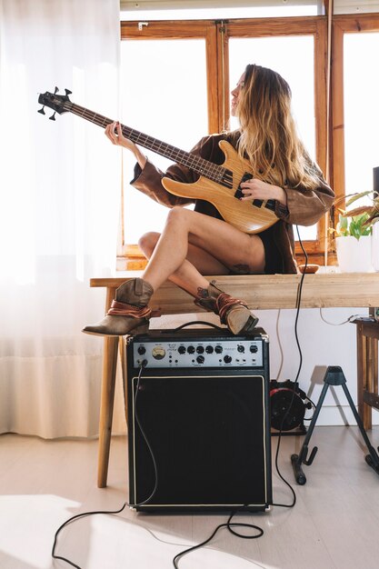 Linda mujer tocando la guitarra en la mesa