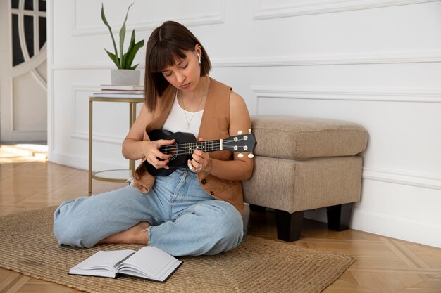 Linda mujer tocando el ukelele en casa