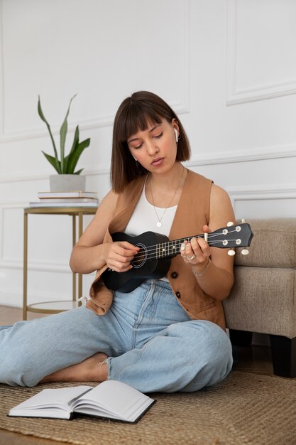 Linda mujer tocando el ukelele en casa