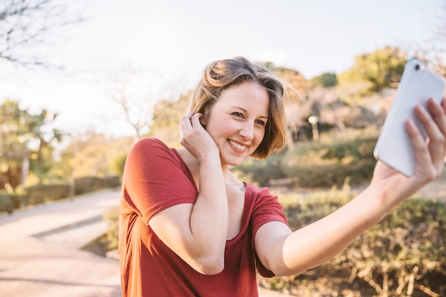 Linda mujer tomando selfie en el parque