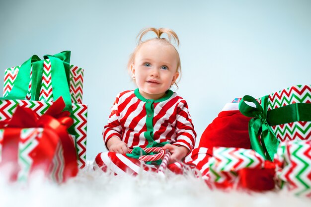 Linda niña de 1 año cerca de gorro de Papá Noel posando en Navidad