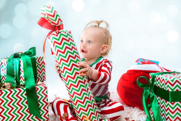 Linda niña de 1 año cerca de gorro de Papá Noel posando en Navidad