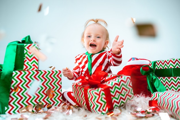 Linda niña de 1 año cerca de gorro de Papá Noel posando en Navidad