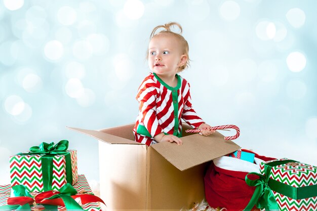 Linda niña de 1 año sentado en caja durante Navidad