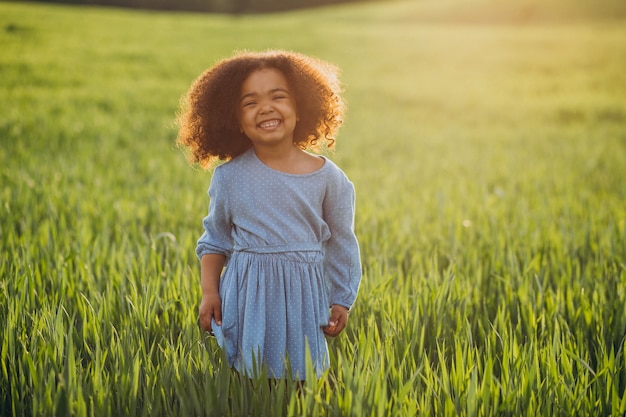 Linda niña africana en el campo en la puesta de sol