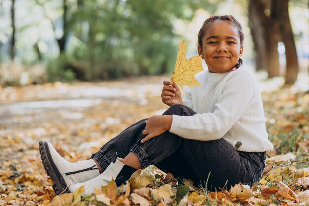 Linda niña africana en el parque otoñal