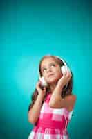 Foto gratuita la linda niña alegre con auriculares en pared naranja