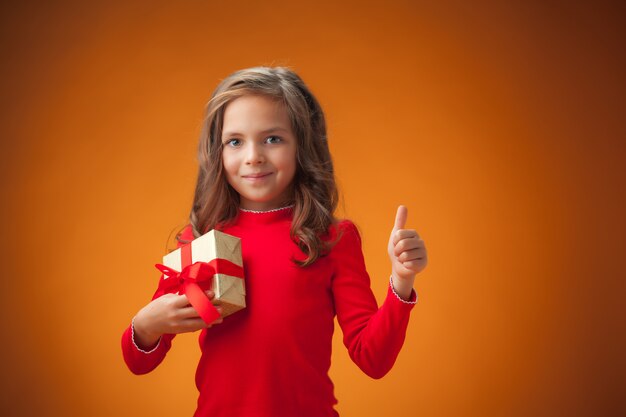 La linda niña alegre sobre fondo naranja