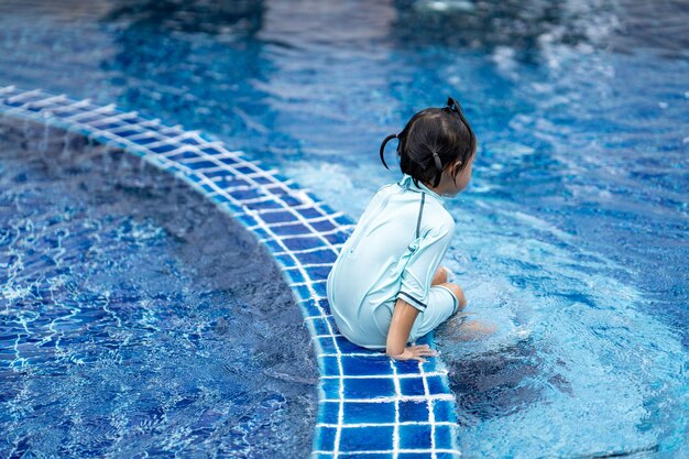 Linda niña asiática en una piscina