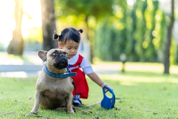 Linda niña asiática con su perro mascota en un parque