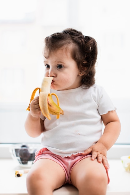 Linda niña comiendo plátano