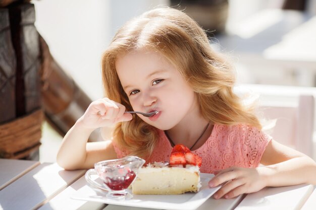 linda niña comiendo postre en la terraza del café