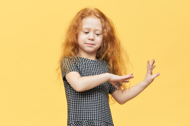 Linda niña europea encantadora en elegante vestido bailando con música, sintiéndose libre