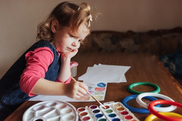 Linda niña feliz, adorable niño en edad preescolar, pintando con agua