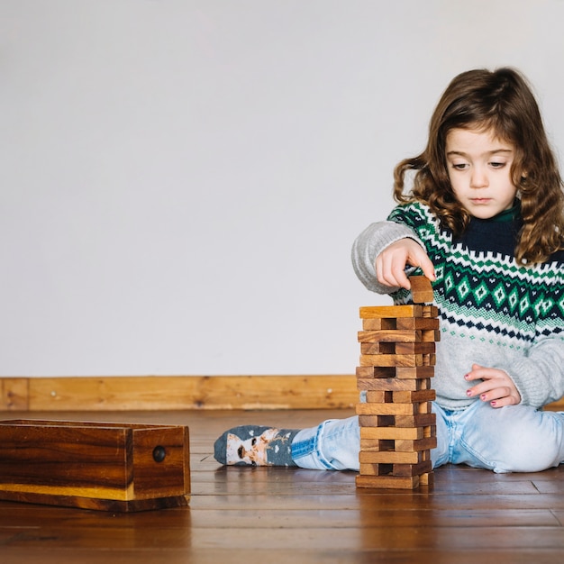 Linda niña jugando juego de bloque de madera