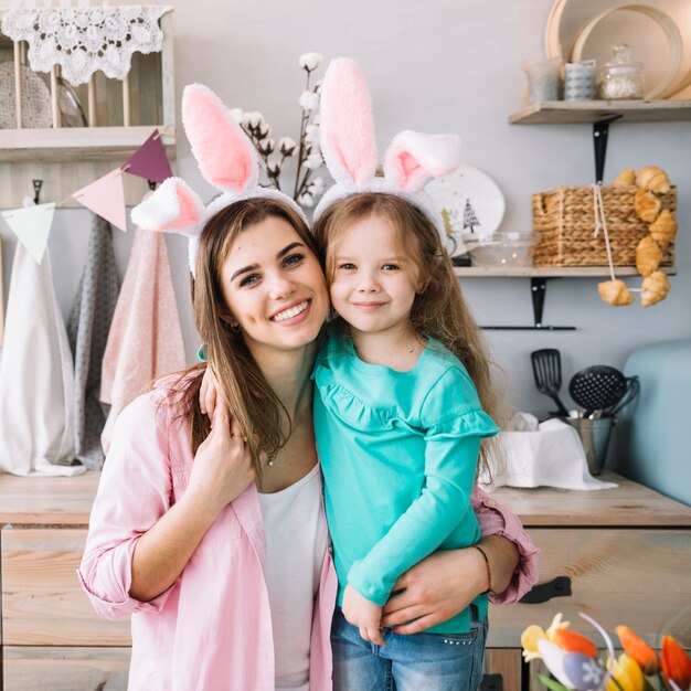 Linda niña y madre abrazando orejas de conejo