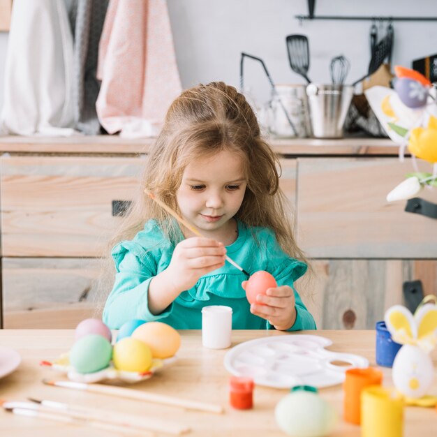 Linda niña pintando huevos para pascua