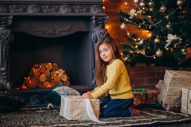 Linda niña con regalos junto al árbol de navidad.