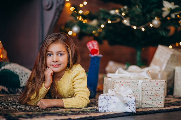 Linda niña con regalos junto al árbol de navidad.