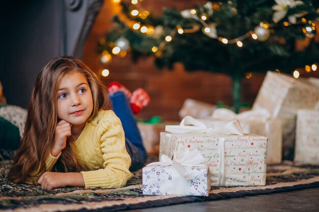 Linda niña con regalos junto al árbol de navidad.