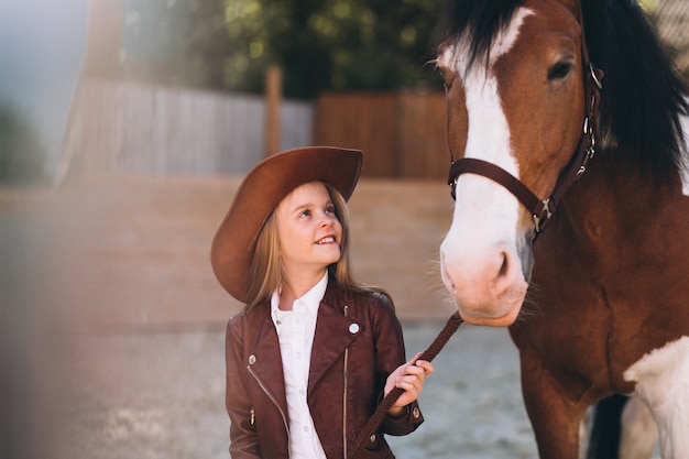 Linda niña rubia con caballo en el rancho