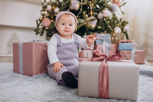 Linda niña sentada junto a regalos de Navidad