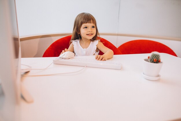 Linda niña sentada a la mesa en una sala de exposición de automóviles