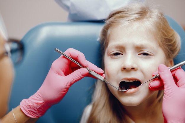Foto gratuita linda niña sentada en la oficina del dentista