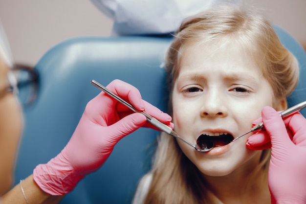 Linda niña sentada en la oficina del dentista