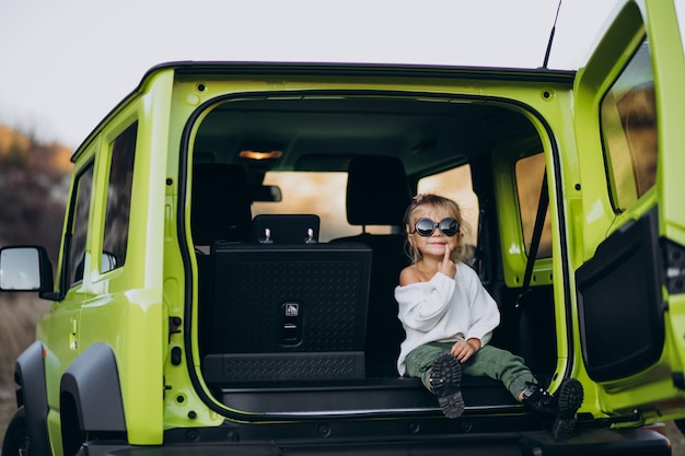 Linda niña sentada en la parte trasera del coche