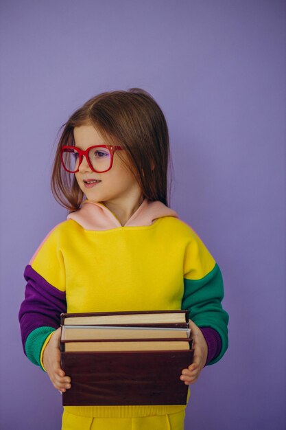 Linda niña sosteniendo libros aislados en estudio