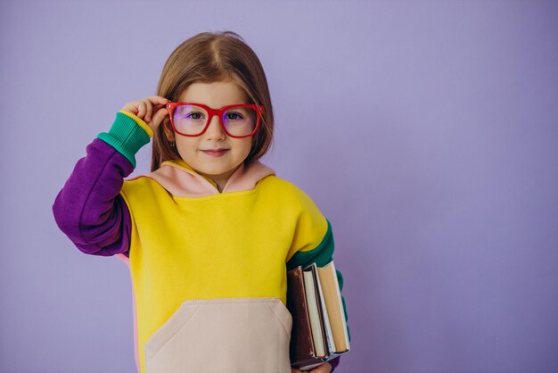 Linda niña sosteniendo libros aislados en estudio