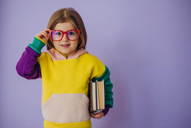 Linda niña sosteniendo libros aislados en estudio