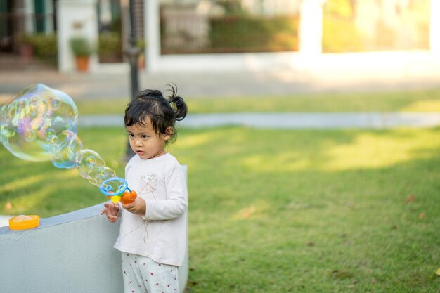 Linda niña tailandesa jugando con pompas de jabón en el parque