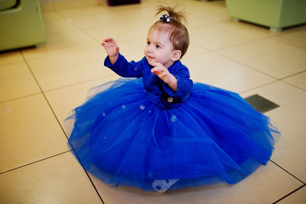 Linda niñita con vestido azul juega con pompas de jabón 1 año de cumpleaños