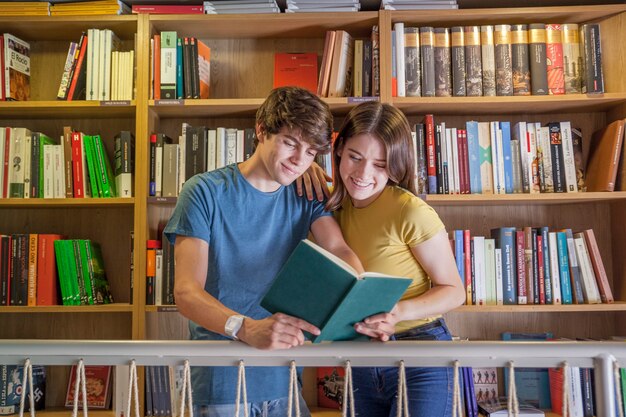 Linda pareja adolescente leyendo en la biblioteca