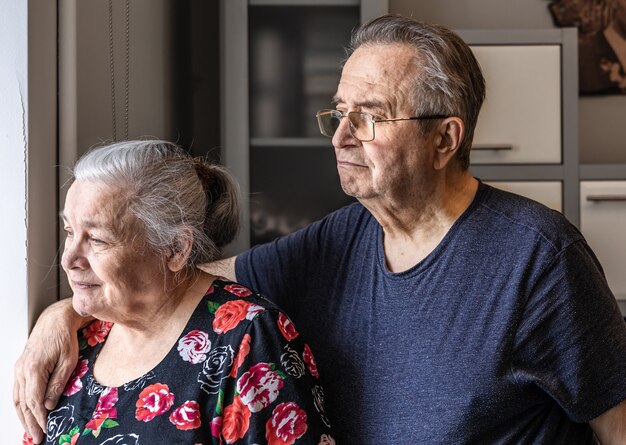 Una linda pareja de ancianos se para en la ventana y busca a alguien, esperando.