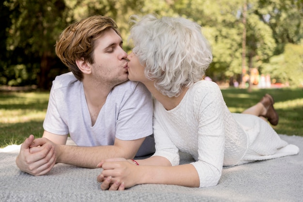 Foto gratuita linda pareja besándose al aire libre sobre una manta