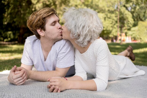 Linda pareja besándose al aire libre sobre una manta