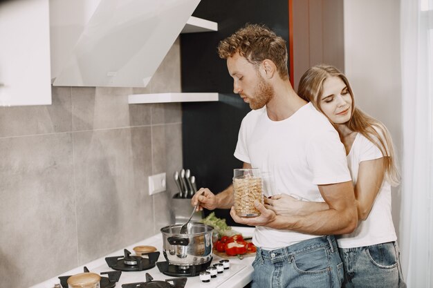 Linda pareja en casa. Señora con una camiseta blanca. La gente prepara una ensalada.