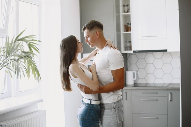 Linda pareja en una cocina. Señora con una camiseta blanca. Emparejar en casa