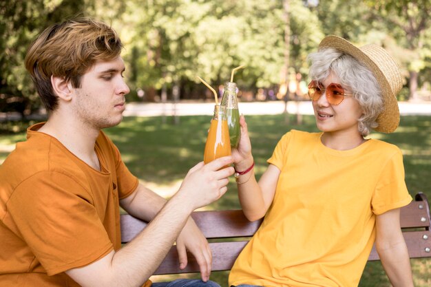 Linda pareja compartiendo jugo al aire libre en el parque