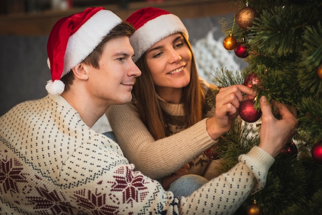 Linda pareja decorando el árbol de navidad