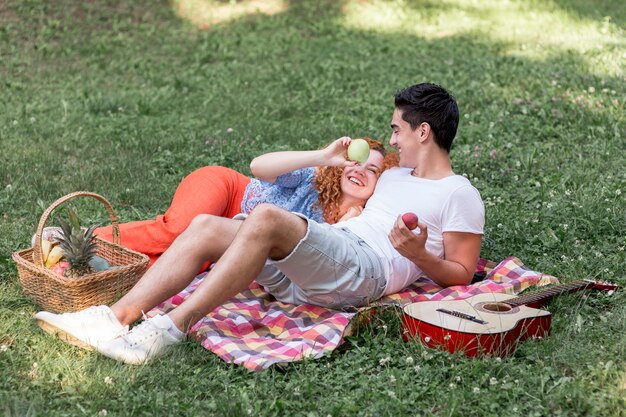 Linda pareja descansando sobre una manta en el parque